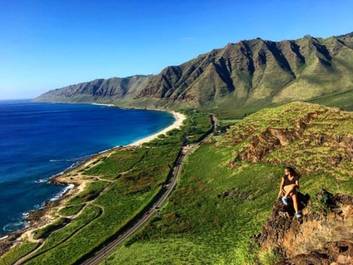 AIFS Au Pair in Hawaii sitzt im Gebirge mit Aussicht auf Meer, Berge und Straße