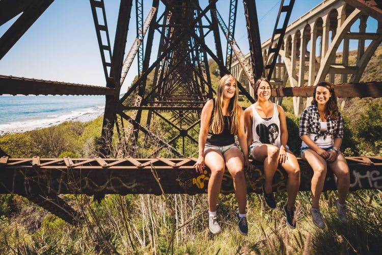 Drei Freundinnen sitzen auf einer Brücke in Australien