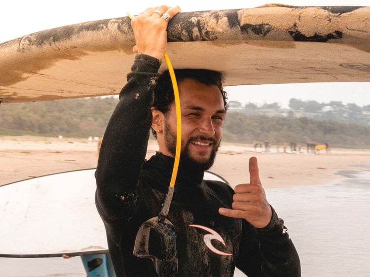 Ein Mann trägt ein Surfboard auf dem Kopf