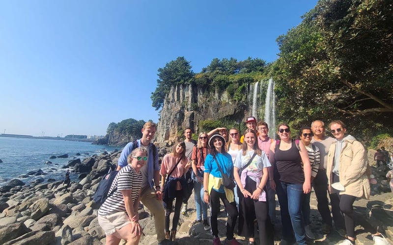 Gruppe vor einem Wasserfall auf Jeju bei der Abenteuerreise in Südkorea mit AIFS