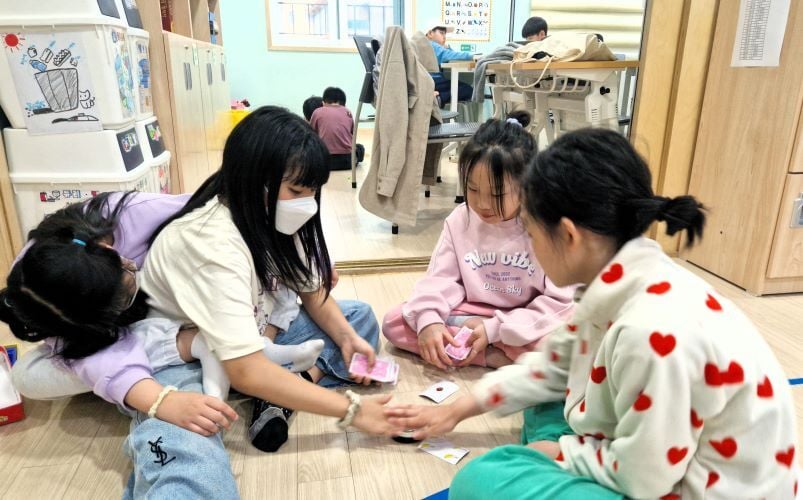 Kinder spielen Karten beim Freiwilligenprojekt Childcare in Südkorea mit AIFS