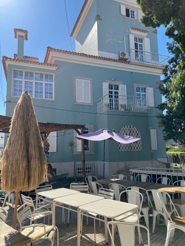 Unterkunft von aussen mit Innenhof mit Tischen und Stuehlen