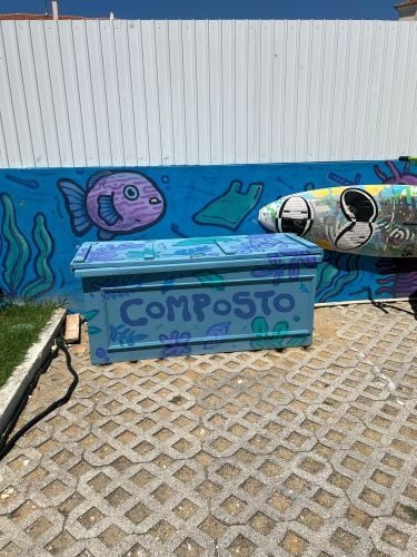 Eine Kiste auf der Strasse, im Hintergrund ein Wandgemaelde mit Fischen und Algen