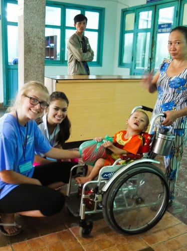 Teilnehmende beim Medical Freiwilligenprojekt in Vietnam bei einem Kind im Rollstuhl