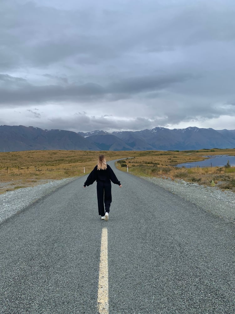 Lena auf einem verlassenen Highway mit Blick auf die neuseeländischen Southern Alps