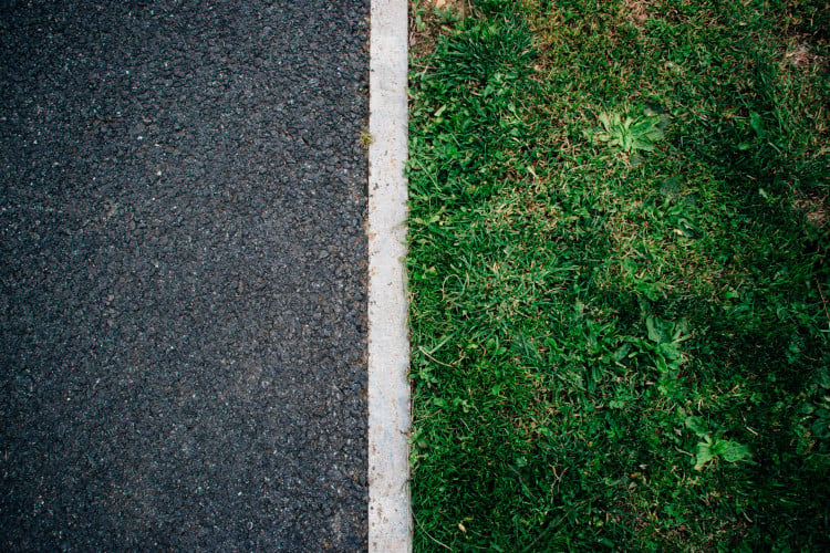 Bild einer Grenze, auf der einen Seite ist Gras und auf der anderen Seite Beton