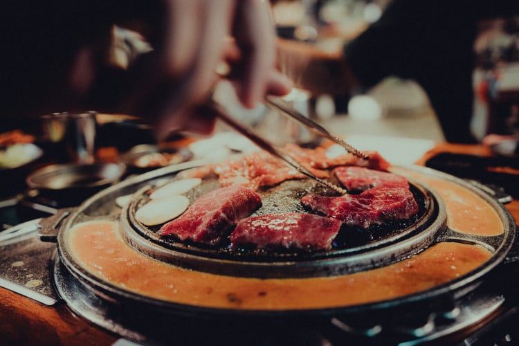 Beim koreanischen Barbecue wird etwas Fleisch auf dem kleinen Tischgrill gebraten 