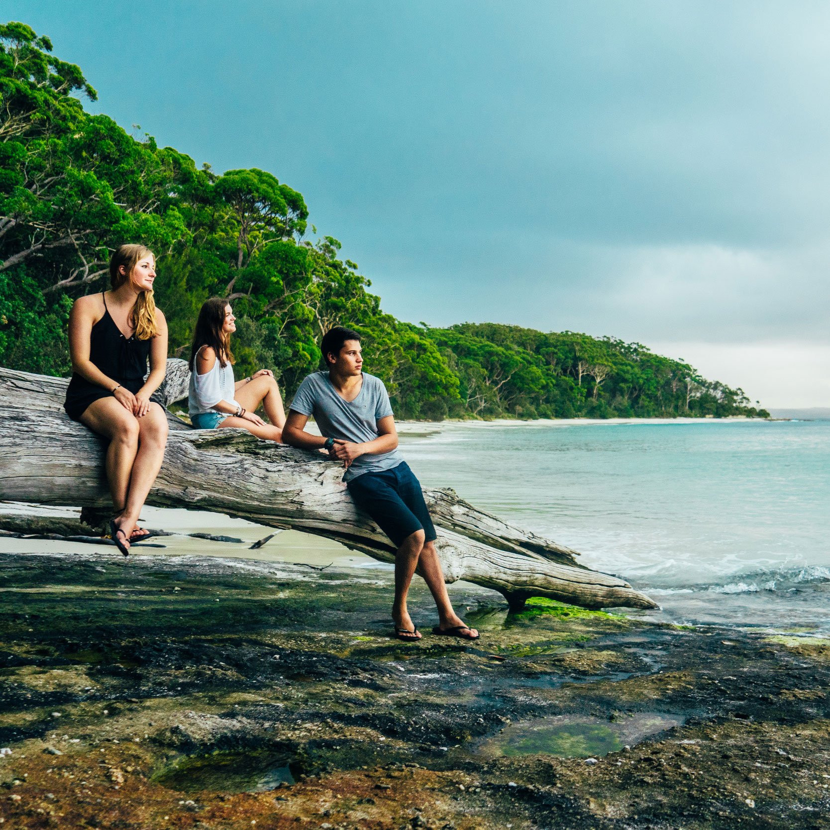 AIFS Australien: Drei Personen genießen sonnige Tage am Strand, umgeben von Meer und unvergesslichen Abenteuern.