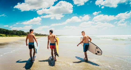 AIFS Australien: Menschen genießen das Meer am Strand mit Surfbrett – erlebe unvergessliche Abenteuer mit AIFS Educational Travel