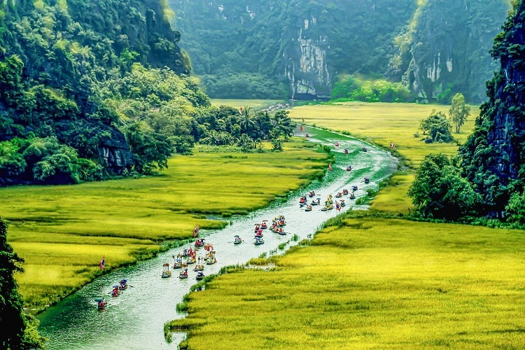 Menschen fahren in Booten durch die Landschaft von Ninh Binh