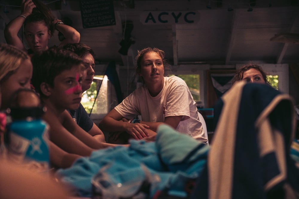 AIFS Camp Betreuerin mit den Kindern bei einer Hütte im Sommercamp