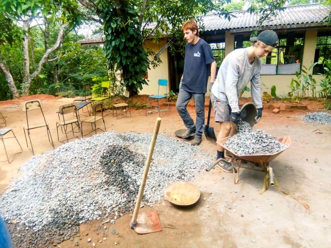 Freiwillige in Sri Lanka transportieren Materialien mit einer Schubkarre im Renovation & Construction Projekt von AIFS.